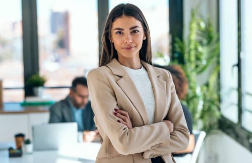 Portrait of beautiful young business woman standing while smiling looking at camera in the office